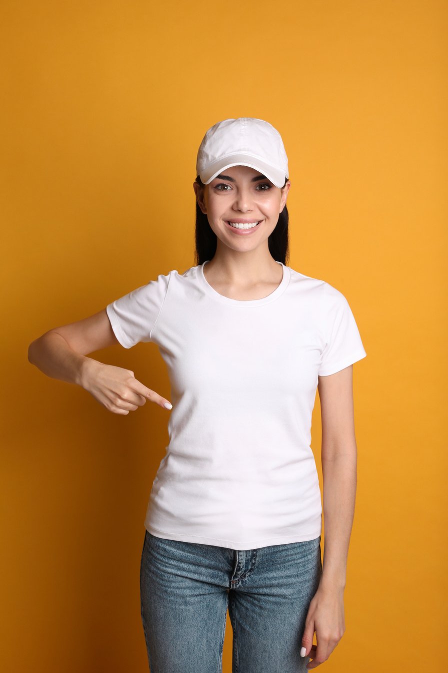 Young Happy Woman in White Cap and Tshirt on Yellow Background.